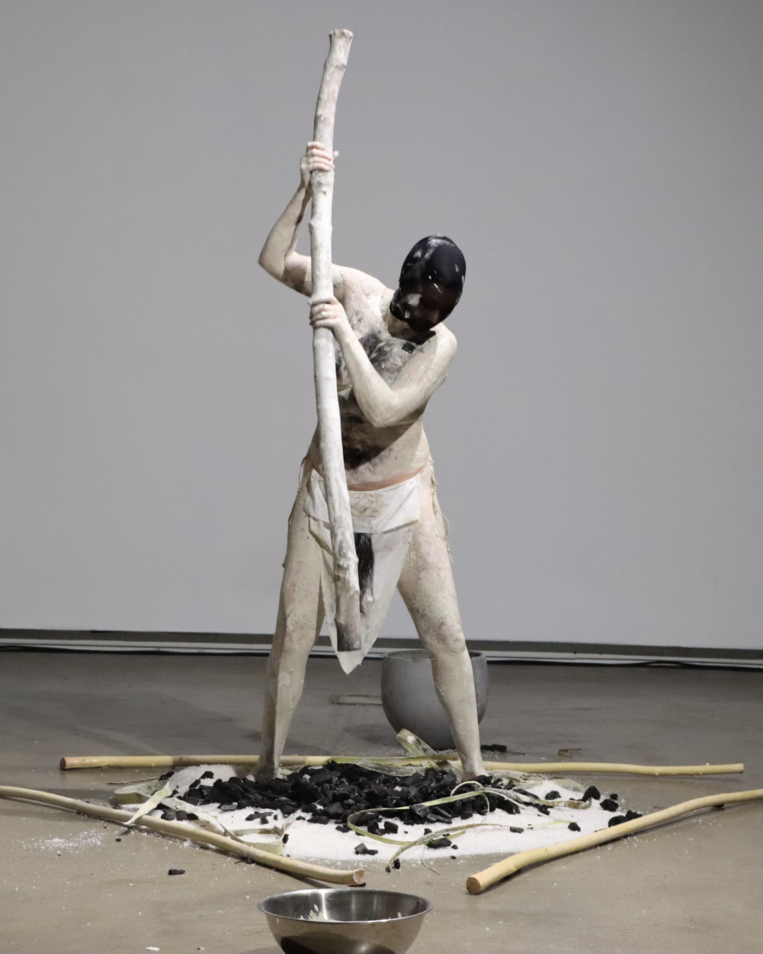 1d - Trust - Sandra Corrigan Breathnach - Unfinished Business - LAI at Source Arts Centre - 2026 - IMG_7985 A person is holding a Mackerel fish up to their face, you can see their head with dark hair and the top of their shoulders.